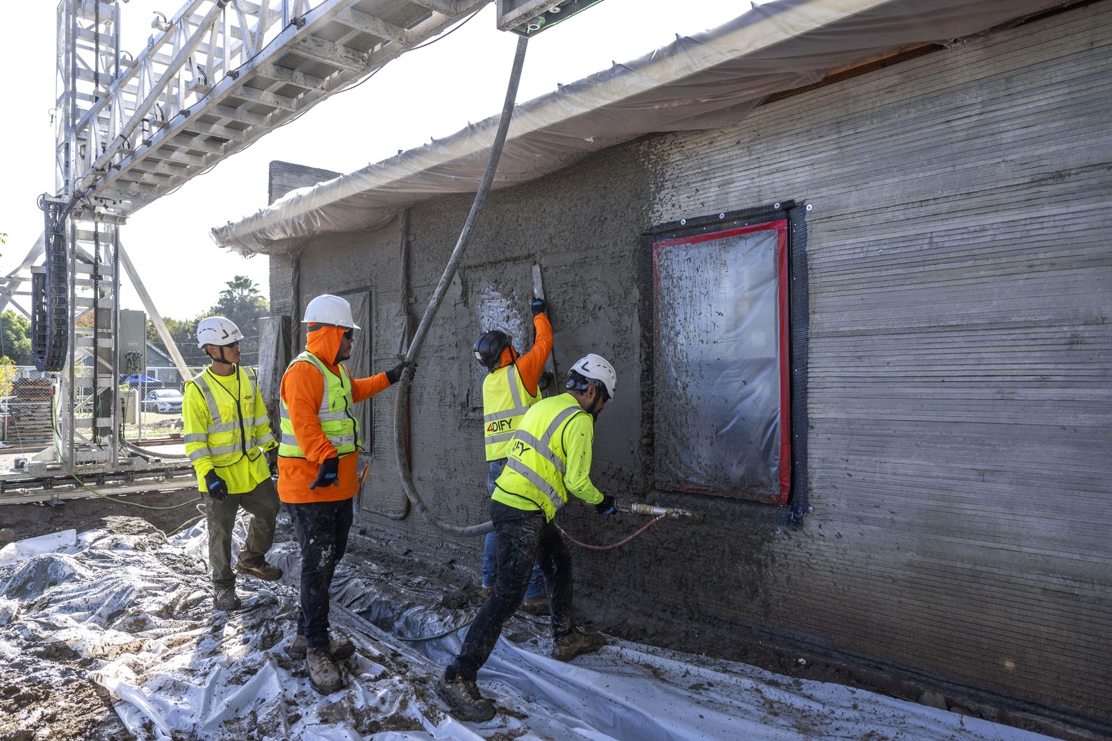 Crew finishing a 3D-printed concrete wall at Kaizen Way